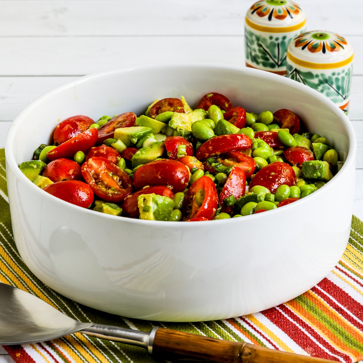 Square image for Tomato Avocado Salad with Edamame, shown in serving bowl.