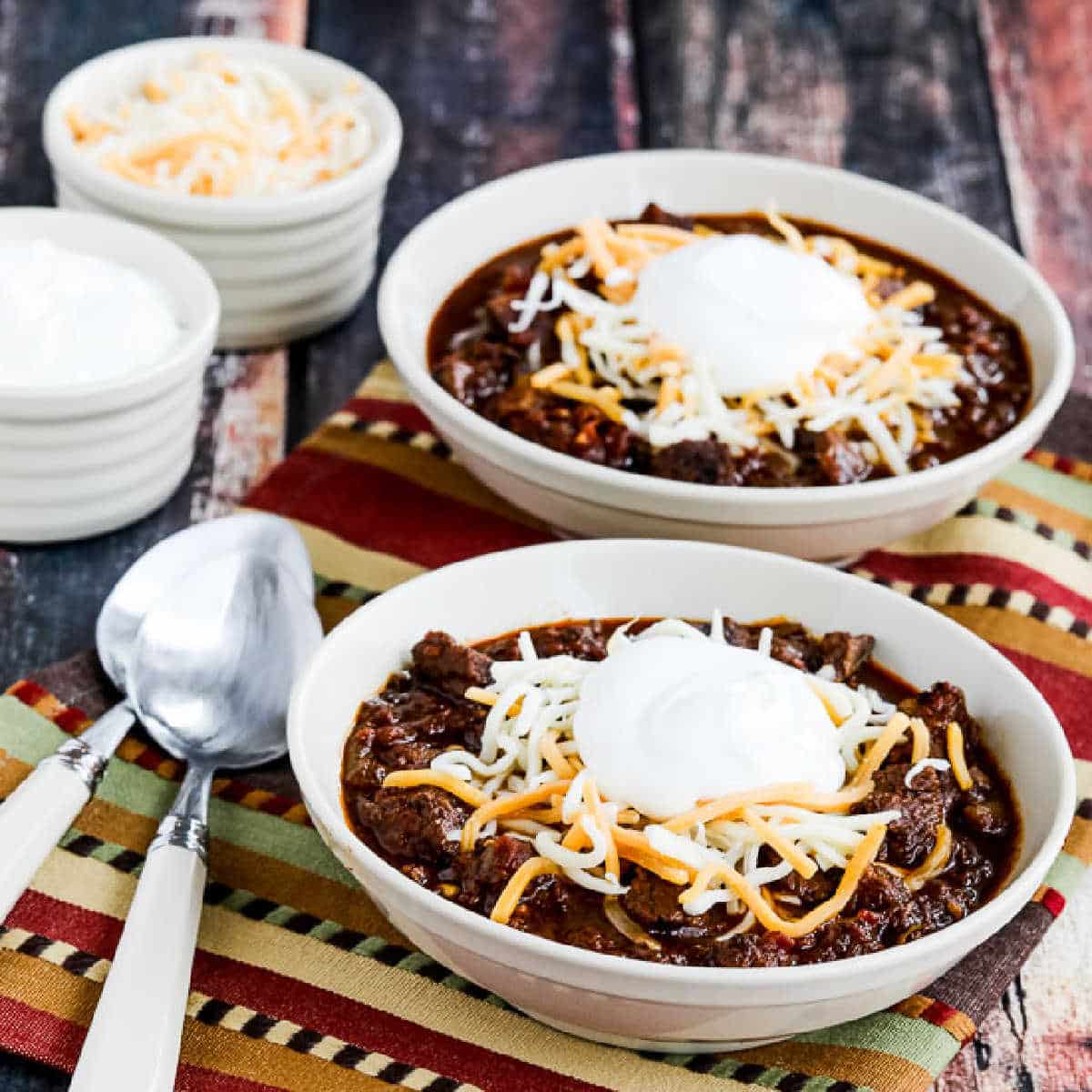 Instant Pot Beef Chili shown in two bowls with cheese and sour cream.