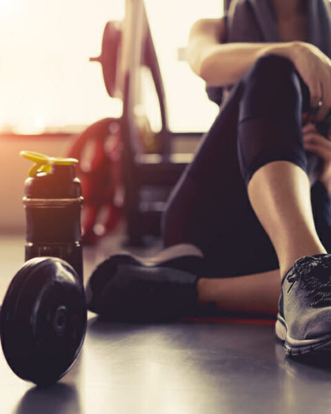 Woman sitting at the gym with dumbbells
