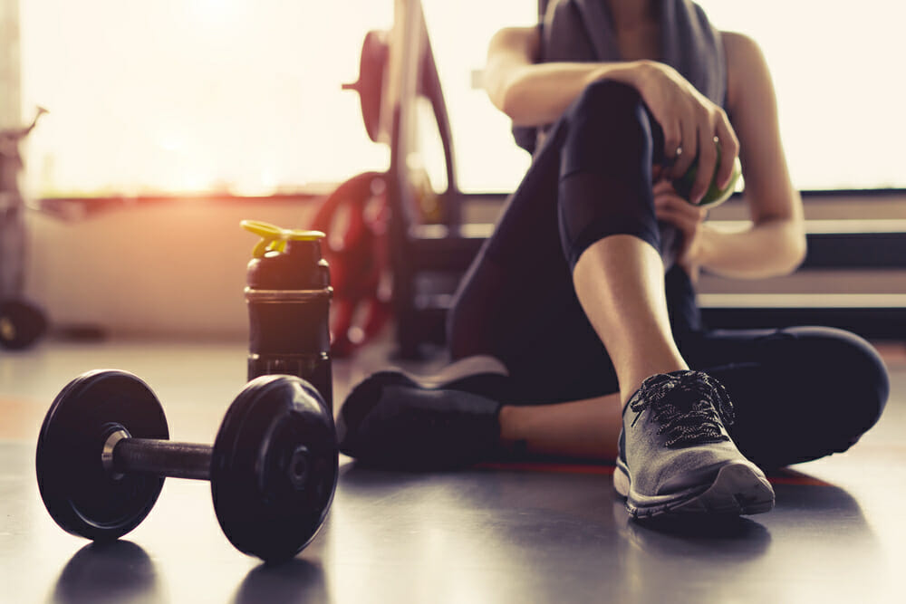 Woman sitting at the gym with dumbbells