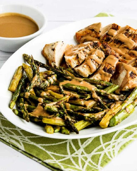 Square image for Chicken and Roasted Asparagus with Tahini Sauce shown on serving platter with sauce in back.