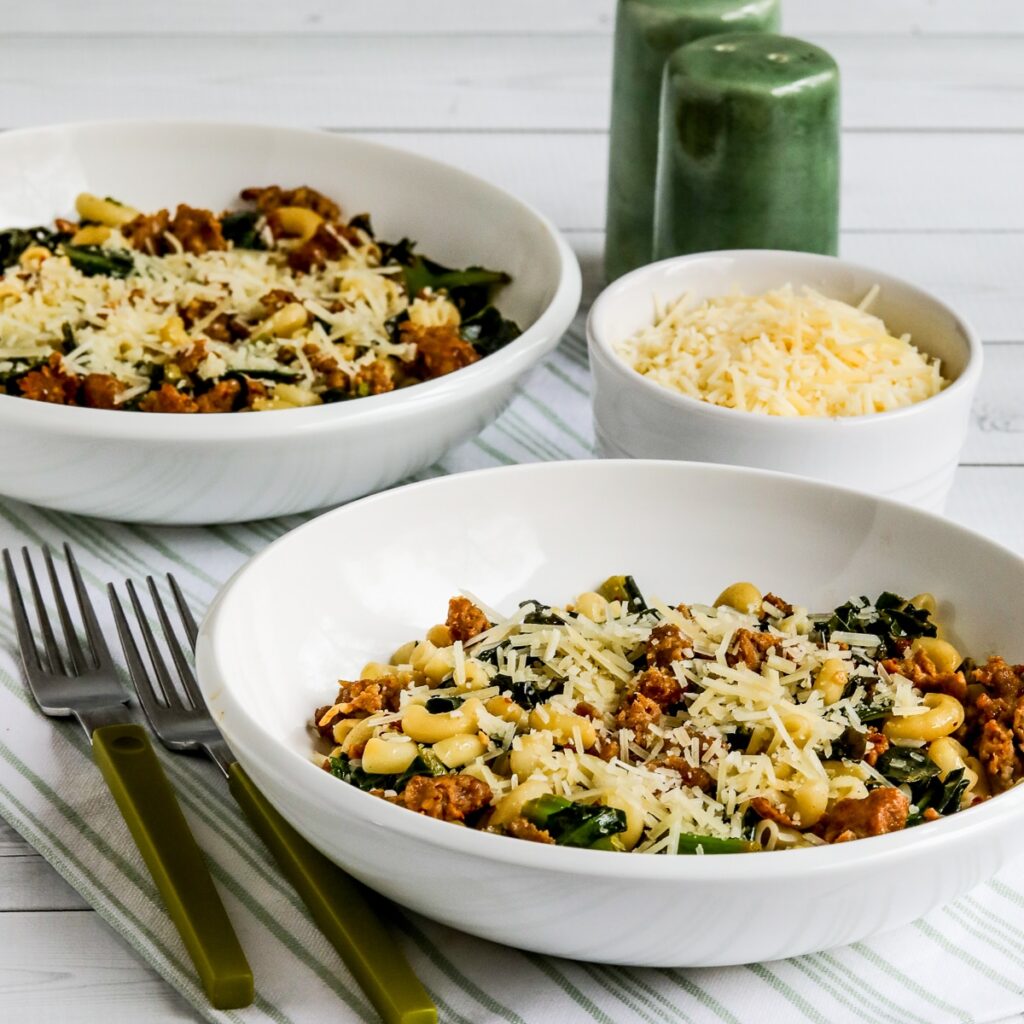 Square image of Italian Sausage Pasta with Collard Greens shown in two bowls.